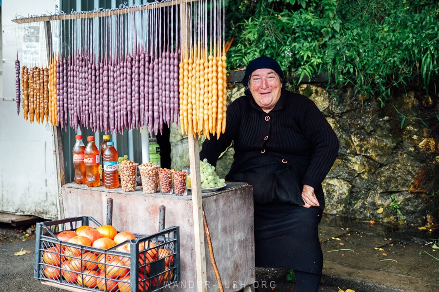 A woman selling churchkhela Georgian candy from a stall on the side of the road.