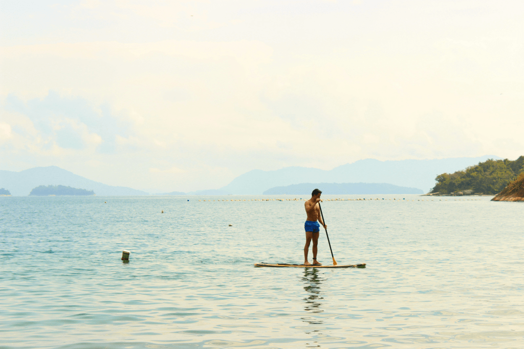 Woman paddle boarding on the beach, Photo By Pedro Sucupira