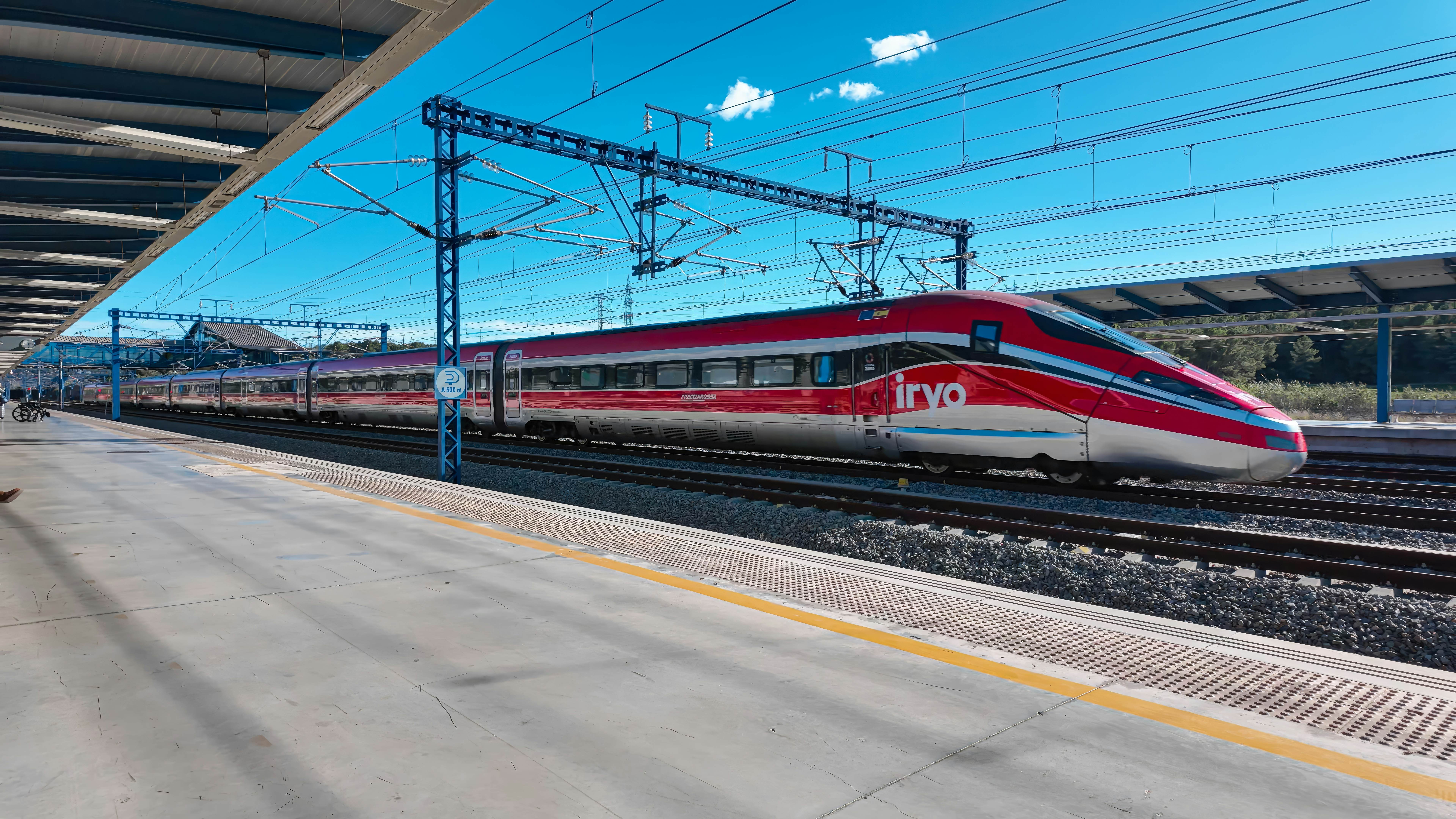 A red train speeds through a station