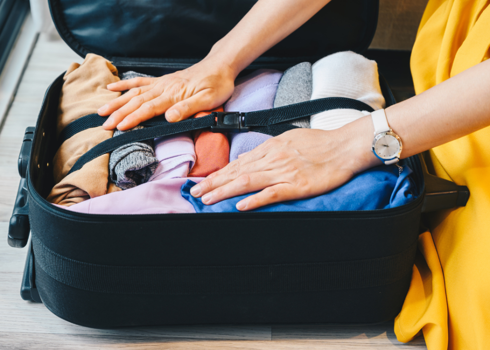 Person organizing suitcase for packing.