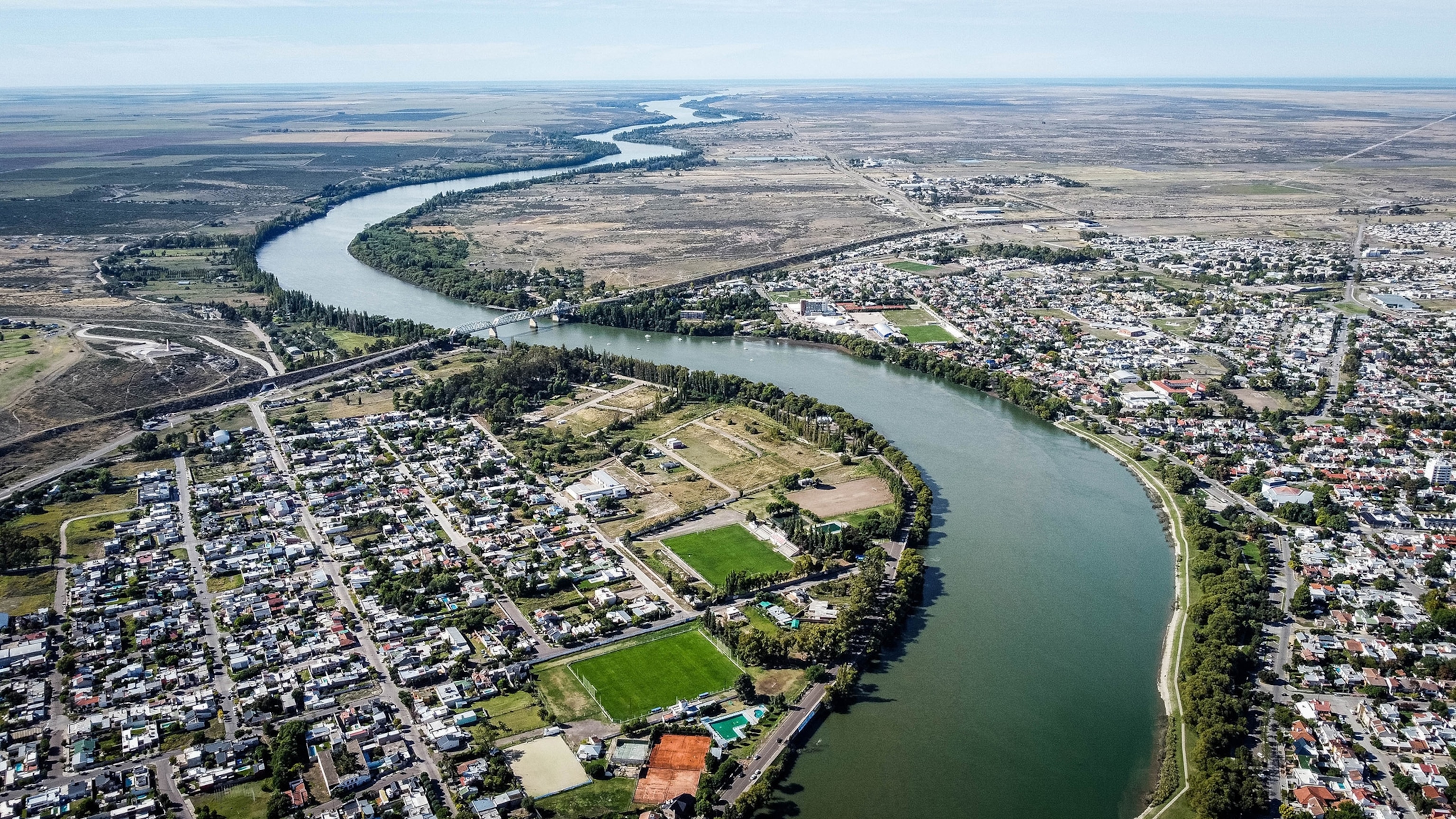 A winding river surounded by greenery and houses.