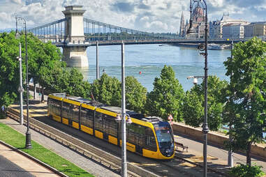 Budapest cityscape with a yellow tram in front of Liberty Bridge