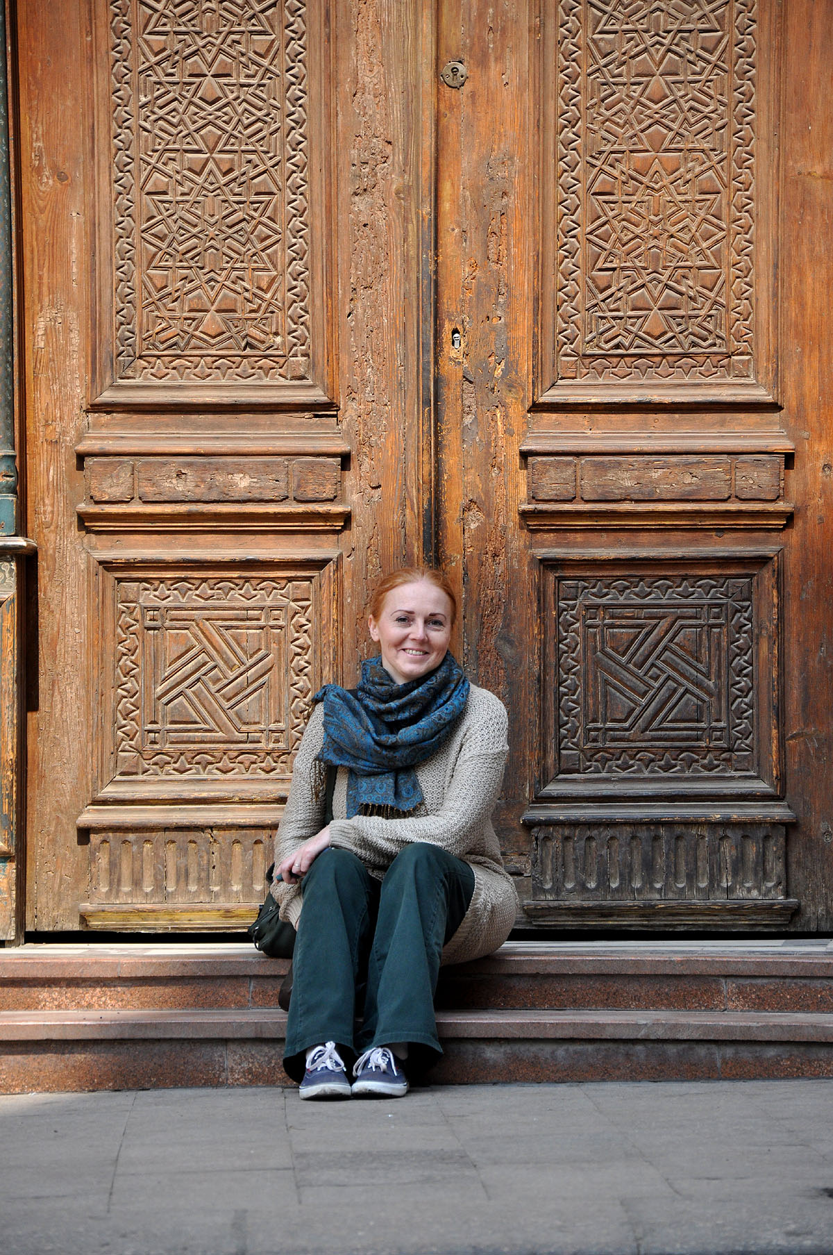 Dee sits on the stairs in front of an ornate wooden door in a building just off Moez Street in Cairo.