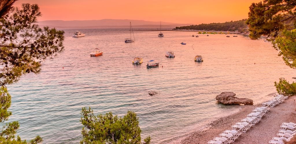 Golden Horn beach in Croatia at dusk, boats line the shore