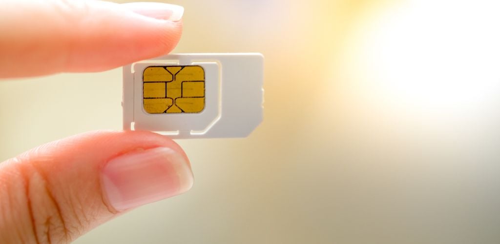 holding sim card between fingers against a light background