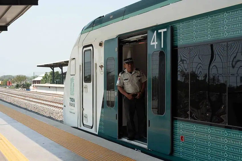 Conductor standing in doorway of Maya Train railroad car