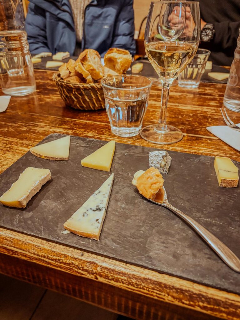 Parisian wine and cheese tasting with assorted French cheeses and white wine.