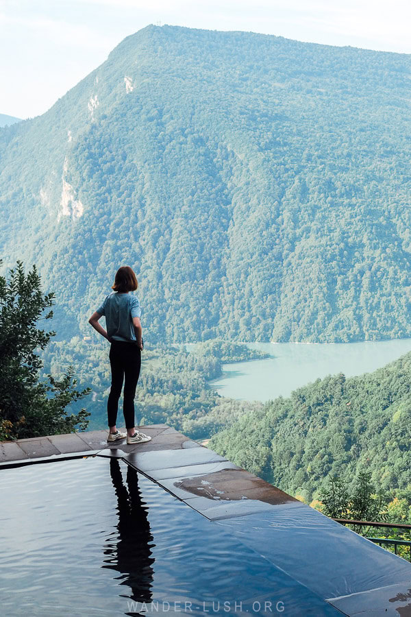 A woman standing on the edge of Lailashi Secret Pool, a beautiful alpine freshwater pool in Lechkhumi.