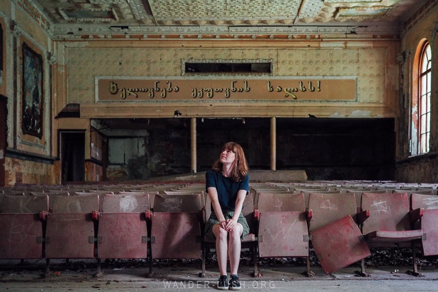Emily sitting on an old theatre seat inside the former culture house in Marani, Georgia.