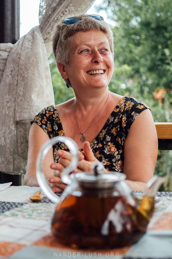 A woman named Lika seated at a table with a pot of fresh Georgian tea, ready for a tea degustation at Komli Guest House.
