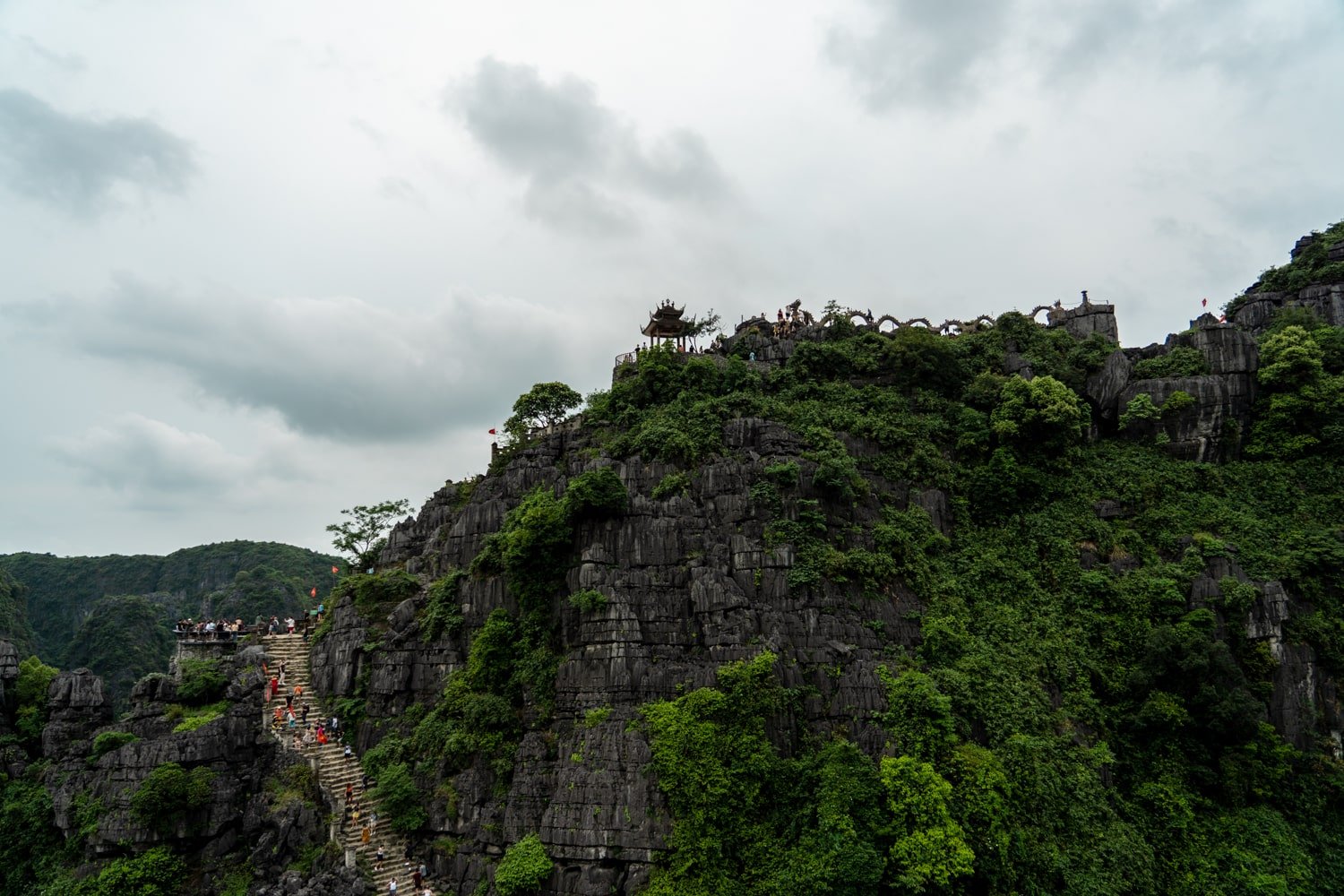 Stone staircase going up Ngao Long Mountain at Mua Caves with dragon statue lying across mountain (Vietnam).