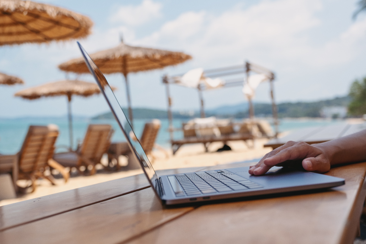 Digital nomad on laptop at table on Bali beach.jpg