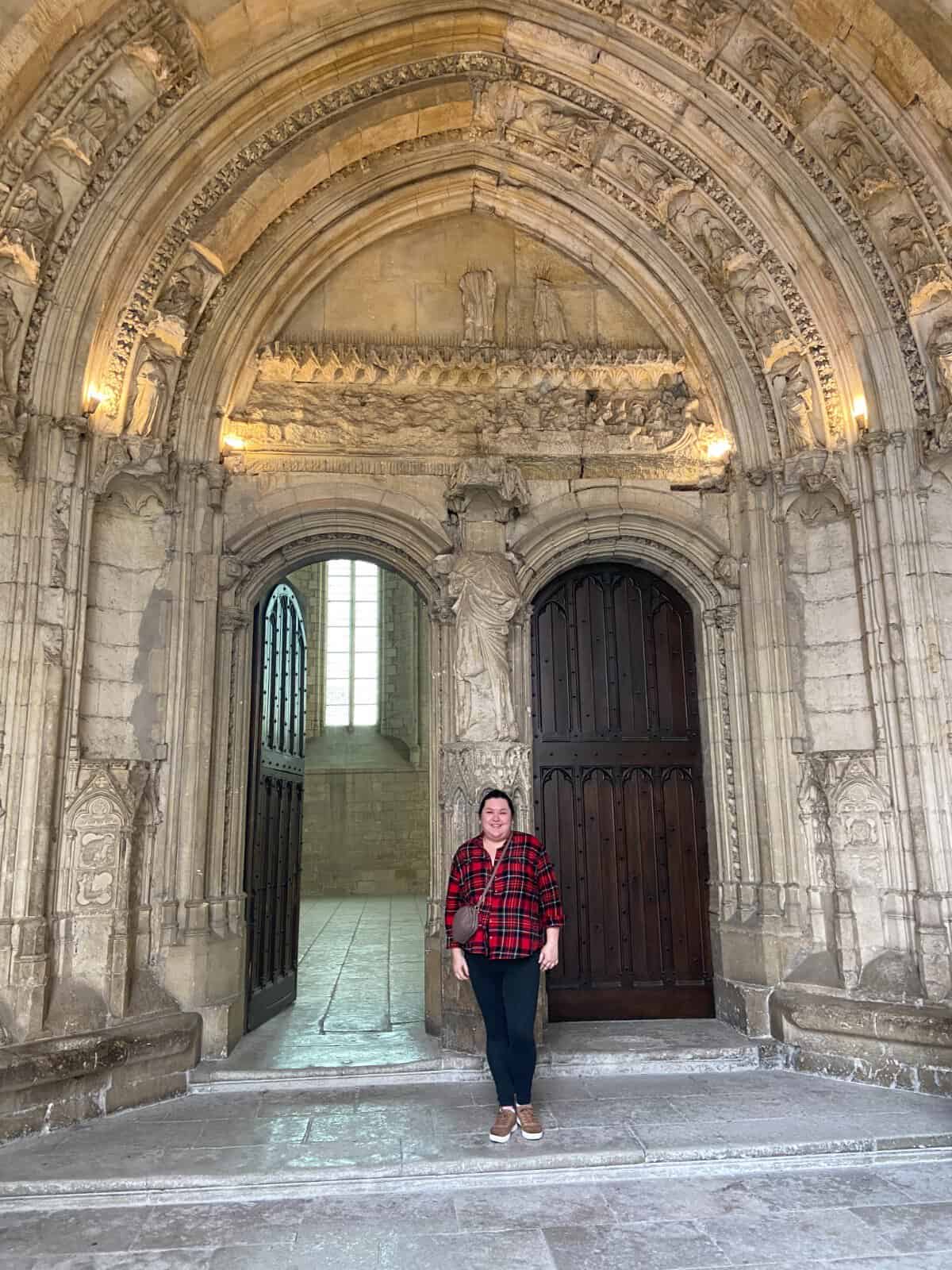 Riana standing in front of an arched doorway inside the Palais des Papes, Avignon, France