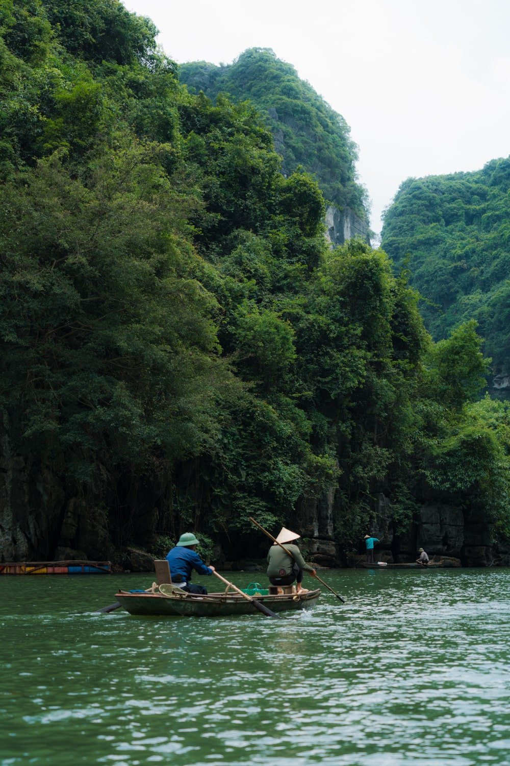 Local Vietnamese men on sanpam boat on the Ngo Long River inside the UNESCO-protected Trang An Scenic Complex Landscape in Vietnam.