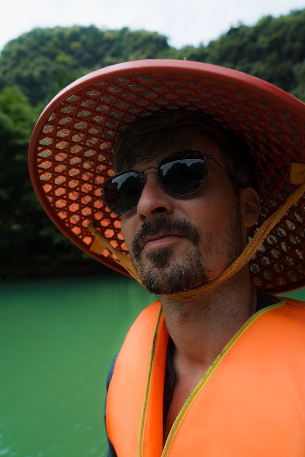 Tourist wearing Vietnamese hat and life jacket on a tour of Trang An.