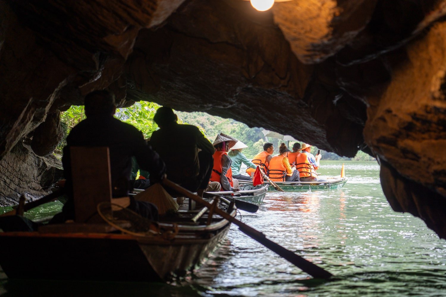 Tourists on the Trang An boat tour in Vietnam exiting low-hanging caves on the Trang An Route 2 tour.