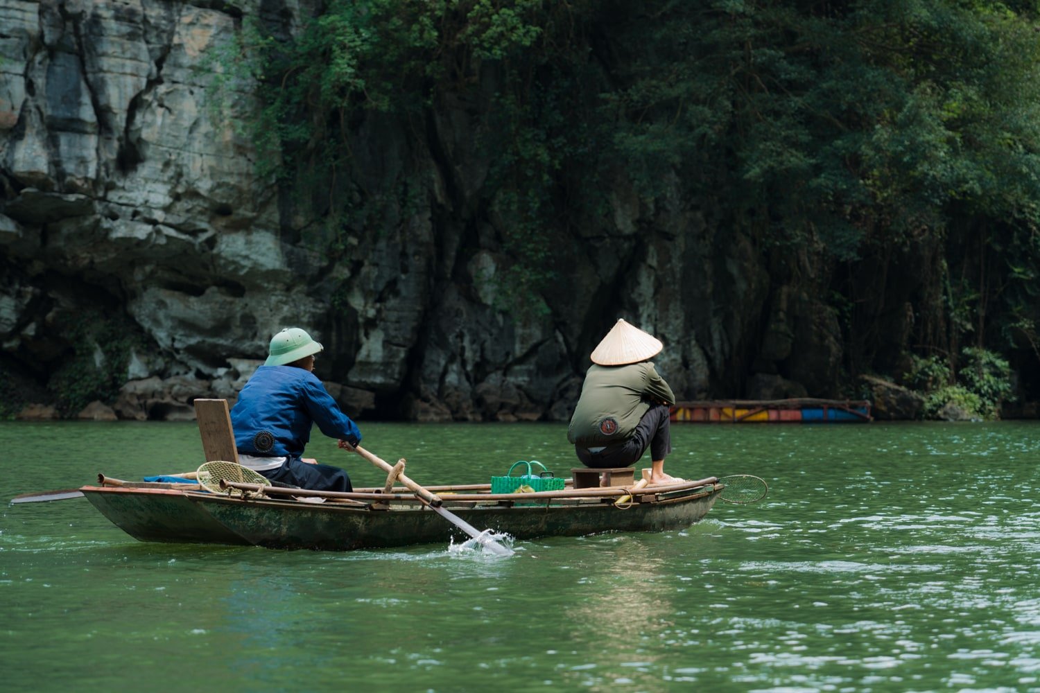 Local Vietnamese men on sanpam boat on the Ngo Long River inside the UNESCO-protected Trang An Scenic Complex Landscape in Vietnam.