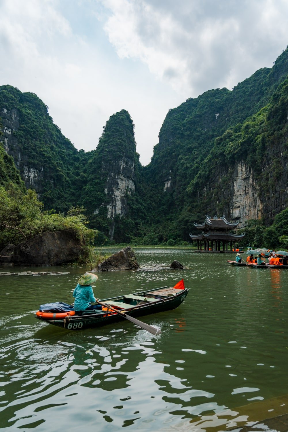 Vietnamese sanpam boats with tourists on the Ngo Long River in front of Suoi Tien Temple in Trang An, Vietnam.