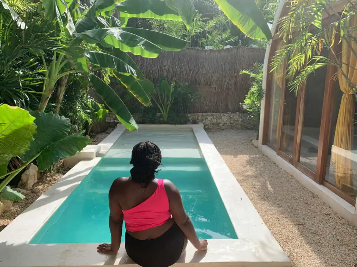 Christina Jane sitting by a pool in Tulum, Mexico