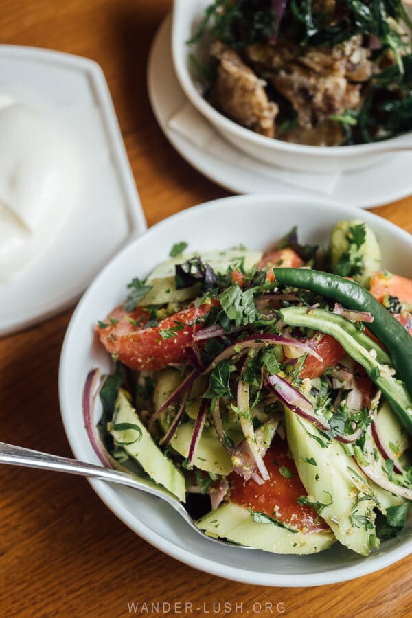 A tomato and cucumber salad with adjika and herbs.