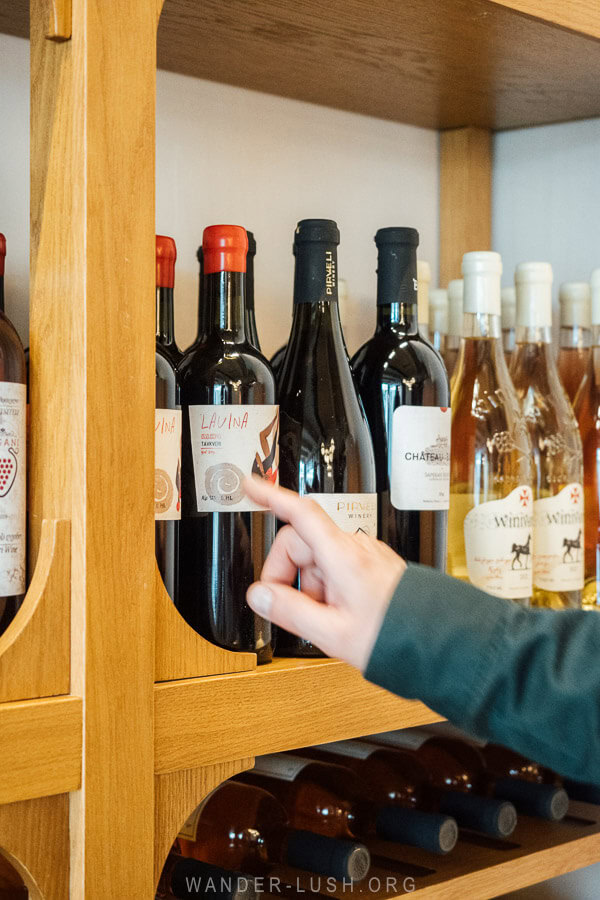 A man points to a bottle of wine on a rack.