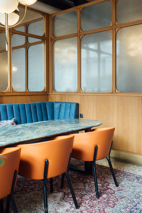 A contemporary dining area with a blue booth and orange chairs.
