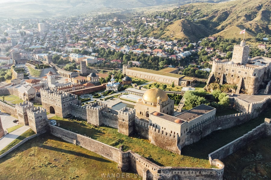 An aerial view of Akhaltsikhe Fotress at sunrise, with the golden-domed mosque in the foreground.