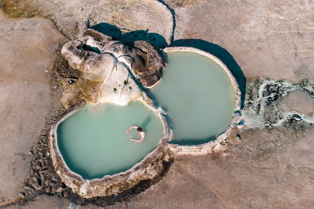 A man swims in two mineral pools filled with light blue sulfur water in Vani, Georgia.