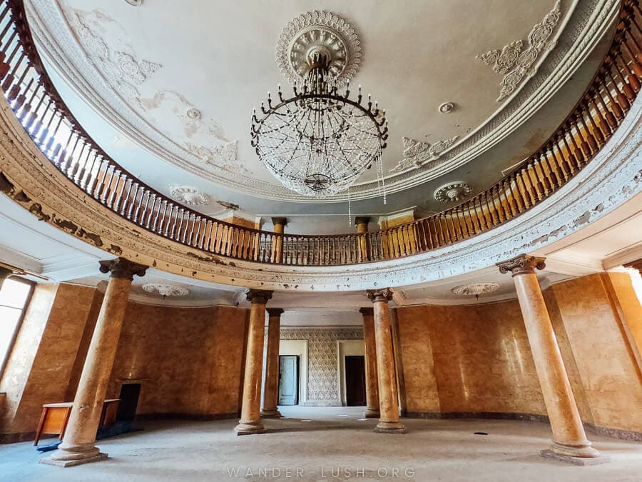 A grand Tskaltubo sanatorium with pillars and a chandelier hanging from the ceiling.