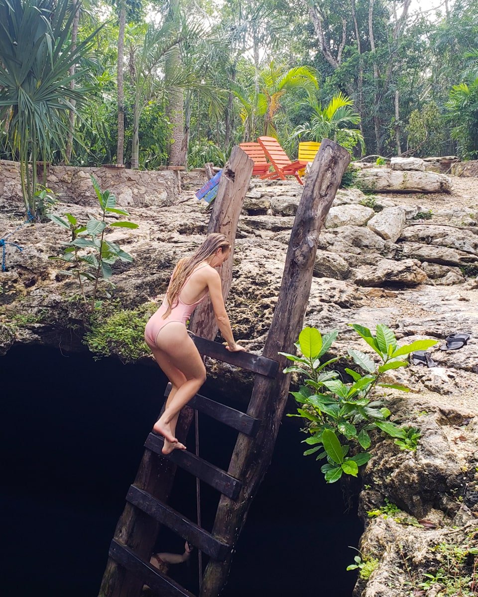 woman climbing ladder in cenote calavera in tulum