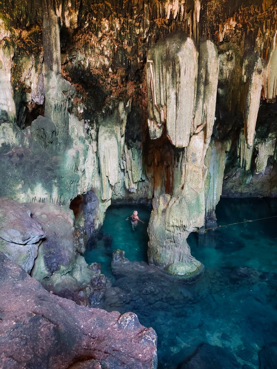 Girl in blue cave water with stalactites. Tza-Ujun-Kat Cenote in Homun and Cuzuma, Yucatan Mexico.