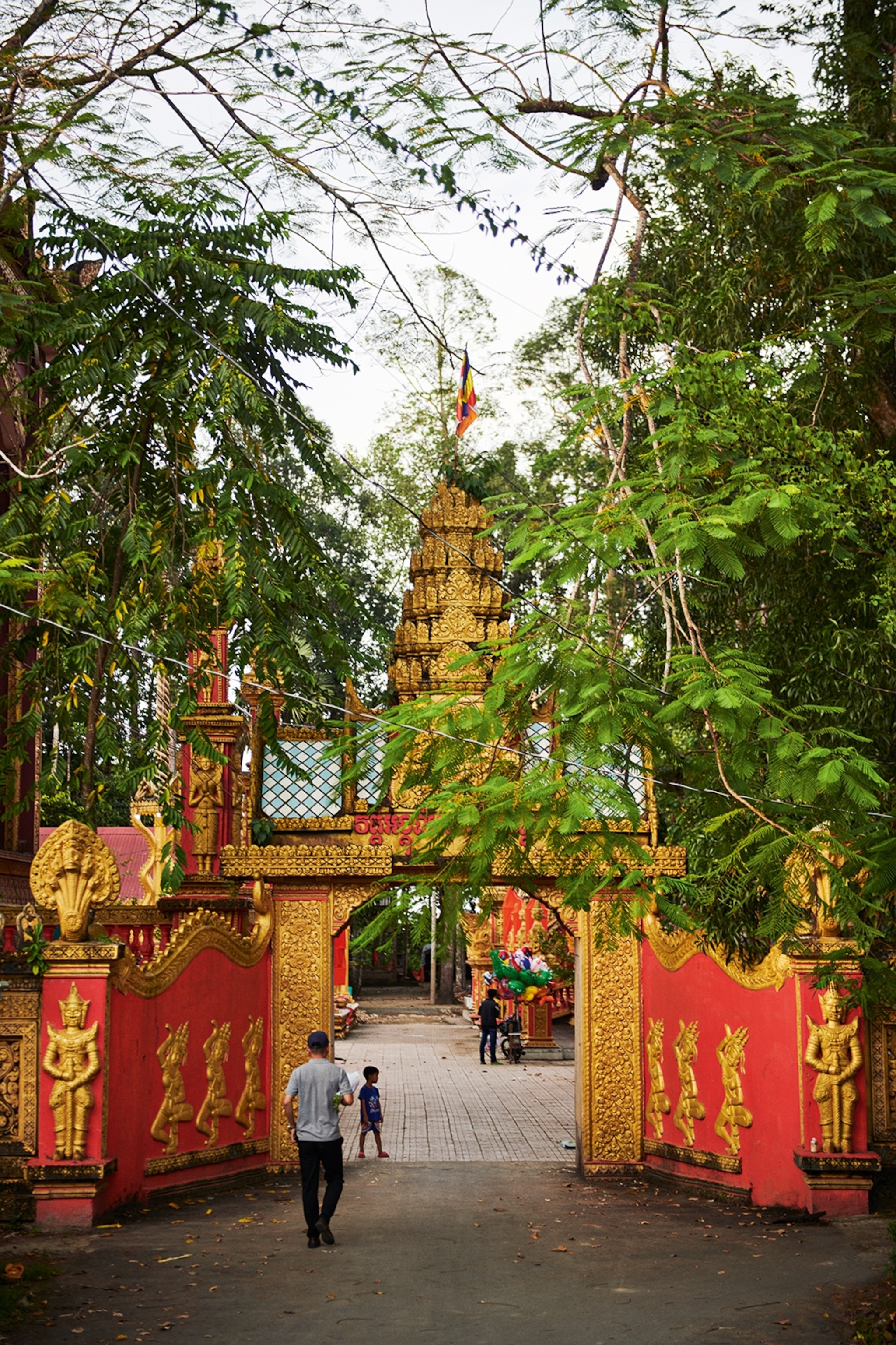 The front view of a Buddhist temple in Vietnam. The doors are painted red with gold embellishments.