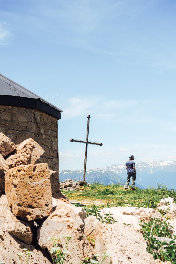 A man standing near a cross on Mount Khvamli.