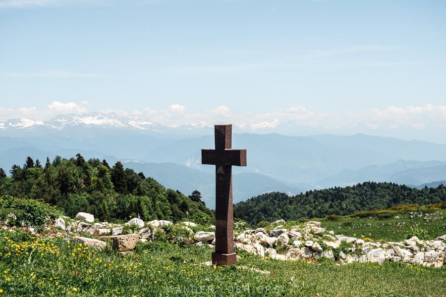 A marble cross mounted on a green hill on Mount Khvamli.