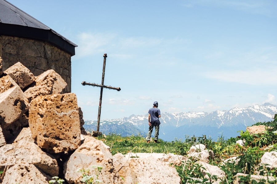 A man stands in front of St George Church on Khvamli Mountain, looking into the distant mountains.