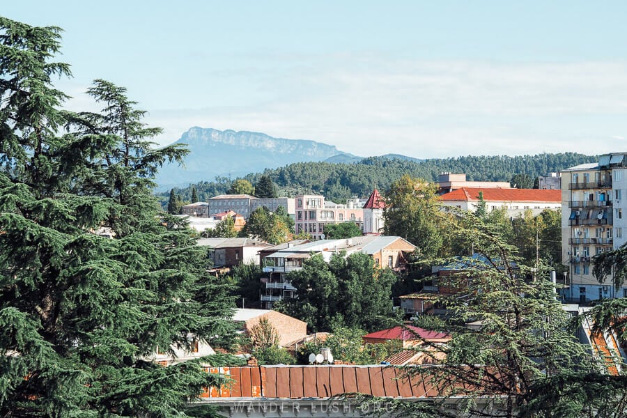 View of Khvamli Mountain, a limestone massif in Lechkhumi with the rooftops of Kutaisi city and green trees in the foreground.