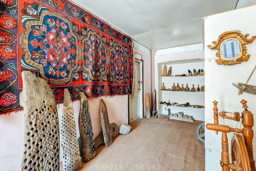 A red and blue carpet with traditional designs hangs on the wall of a museum in Khinaliq, Azerbaijan.