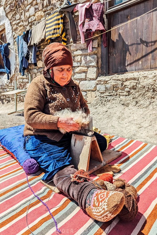 A woman in Khinaliq village uses a tool to separate sheep's wool for knitting.