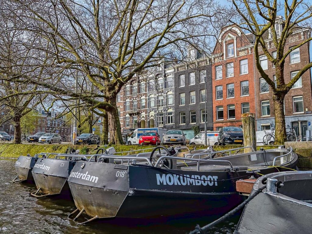 A fleet of Mokumboot rental boats lined along Amsterdam's serene canal