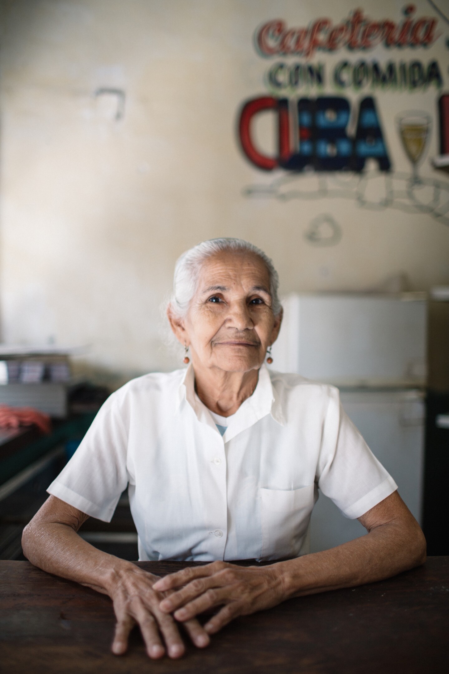 A woman gives a slight smile for Laucht’s camera in a local restaurant in Cuba.