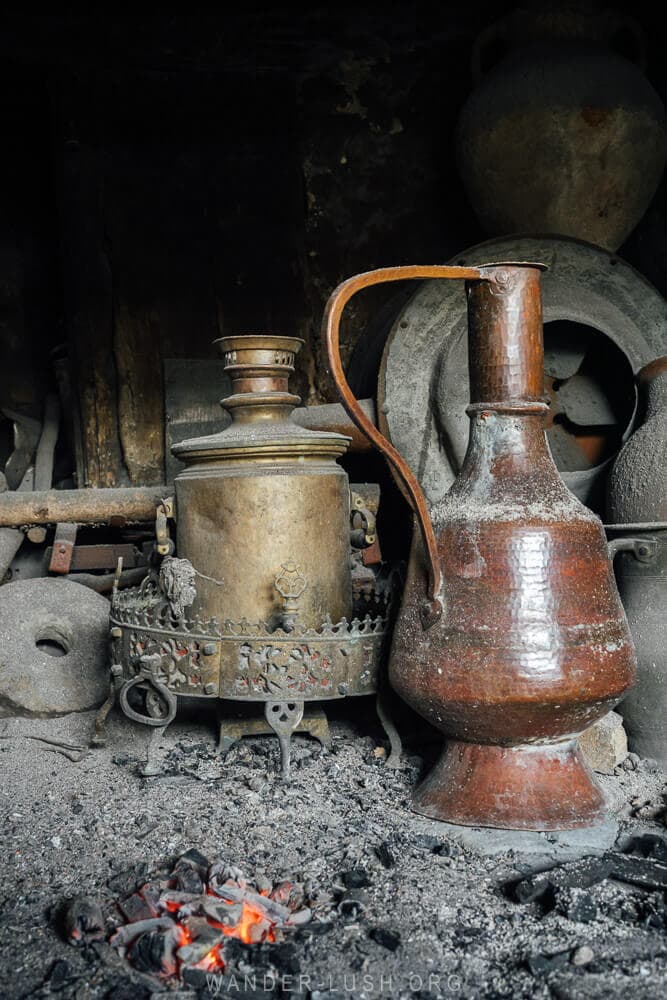 Samovars and jugs sit by a fire.