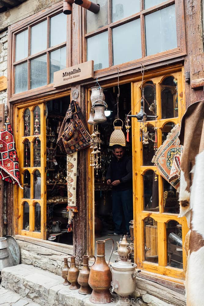 A shop in Lahic, Azerbaijan with carpets and antiques hanging in the windows.