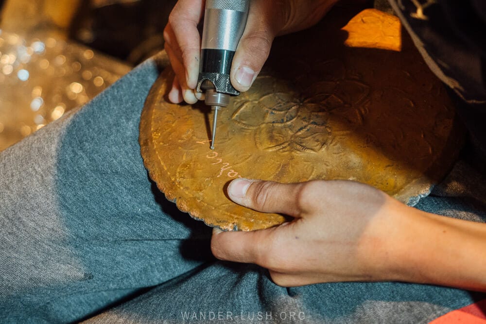 A young man engraving the back of a copper plate.