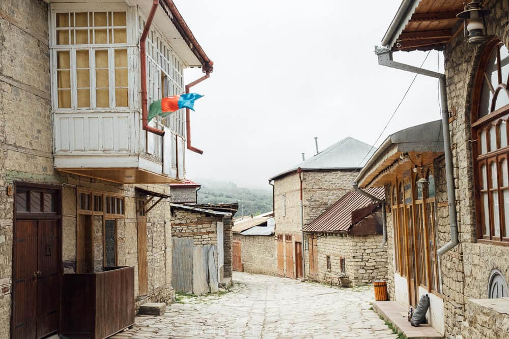 View down a traditional street in Lahic, Azerbaijan, with stone buildings on both sides of a cobbled road.