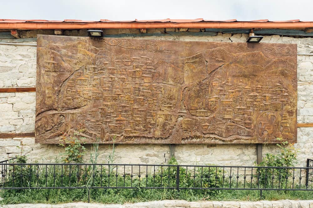 A decorative copper plate mounted to a stone wall in Lahic, Azerbaijan depicts a panorama of the village and its architecture.