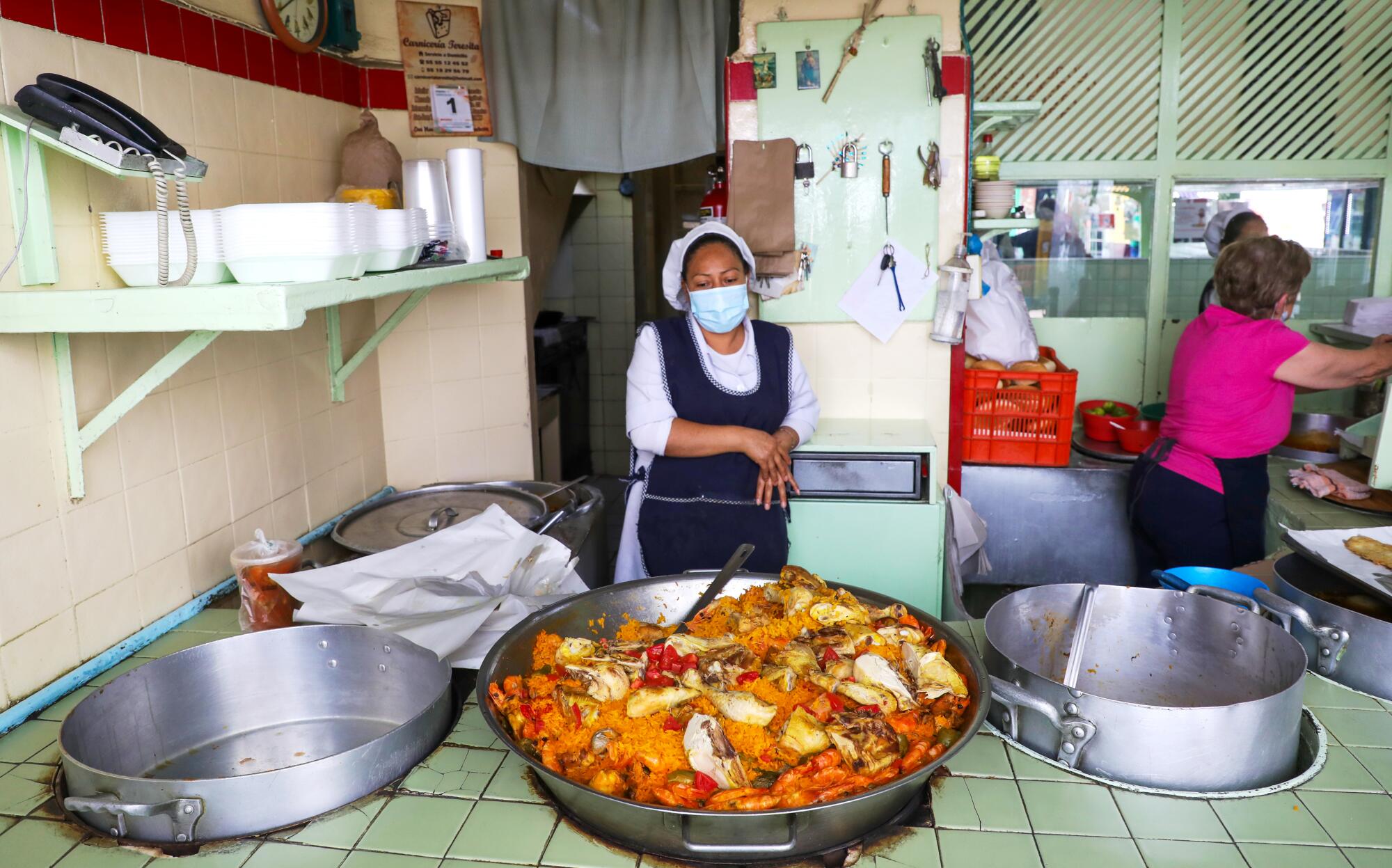 A masked vendor behind a massive pan of paella in Mexico City.