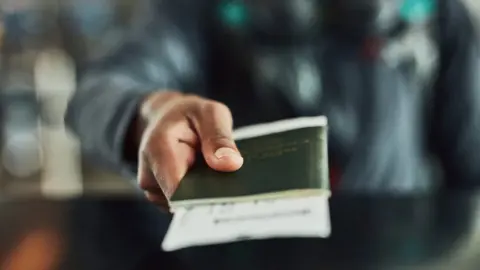 Getty Images Someone handing a passport over