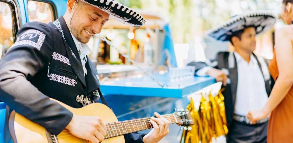 Mexican Musician Wearing Traditional Mariachi and Sombrero playing guitar outdoors 