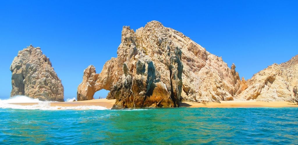 Mexican beach, incredibly blue, turquoise water, rock formation creating an arc, blue, cloudless sky 