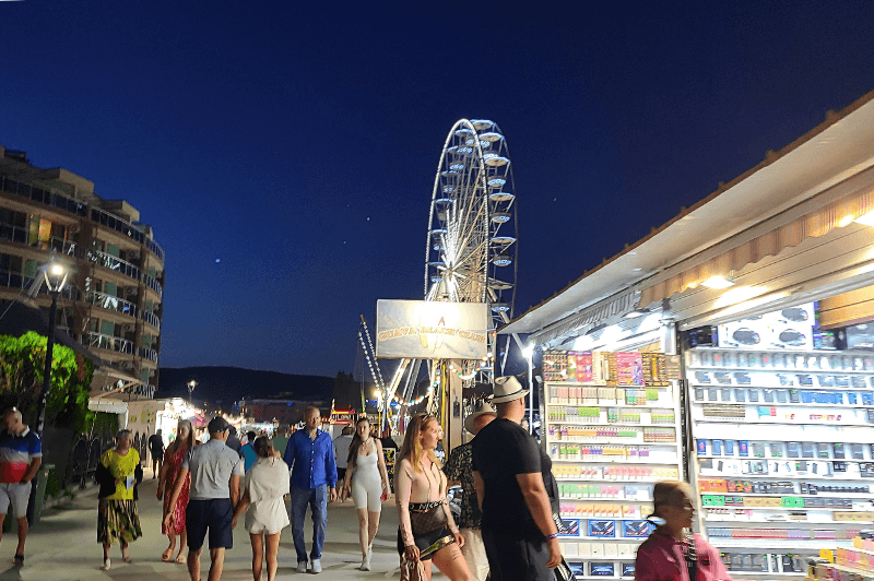 Pop up shops along the Promenade at night in sunny beach bulgaria with the lt up ferris wheel behind.